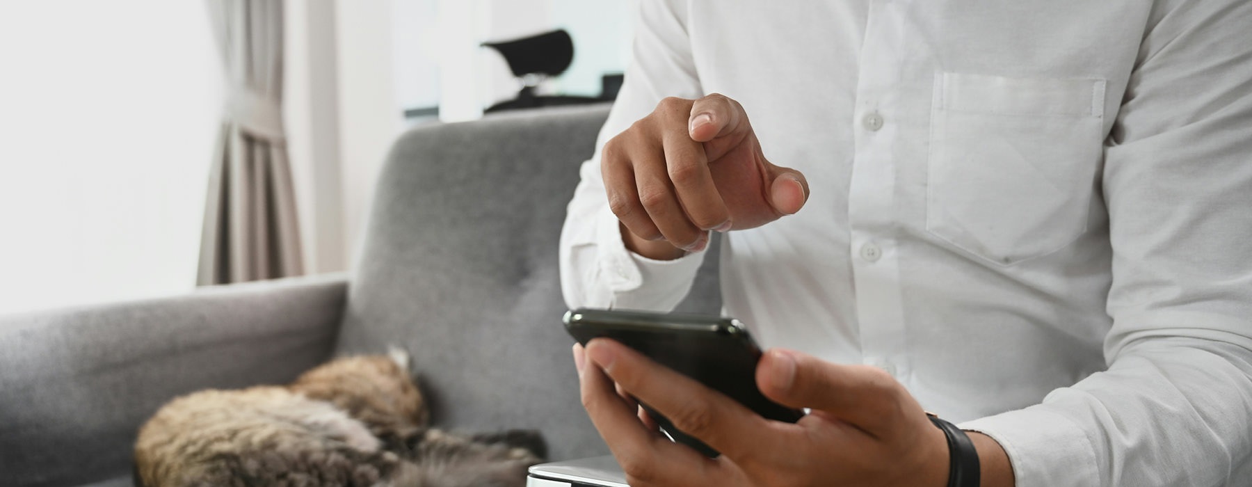 man texts on his phone as he sits on his couch