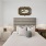 A bedroom with a wall-mounted clock, cozy bed, and soft lighting