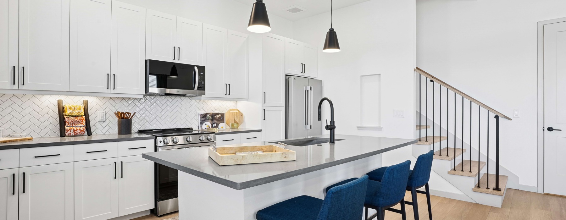 Bright kitchen with white cabinets, stainless steel appliances, and island seating